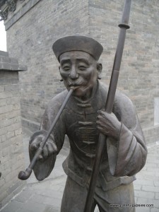 Old school Chinese pipe-smoker statue on the wall.