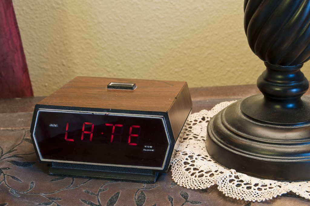 An alarm clock displaying the word "late". This could mean late for work, late for school, late for an appointment or meeting, etc.