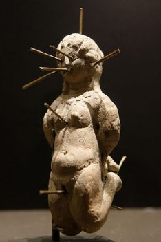 Nude female voodoo doll in kneeling position, bound and pierced with thirteen pins. Found in a terracotta vase with a lead tablet bearing a binding spell (katadesmos). Courtesy of Wikimedia Commons.