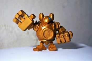 A small plastic figurine of the League of Legend's Blitzcrank champion. Bltizcrank is standing with one hand open and the other closed.