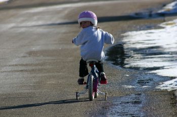 little girl riding a bicycle with training wheels