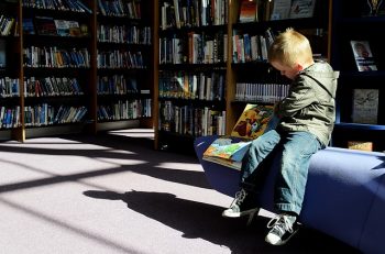 young buy reading a book in a library