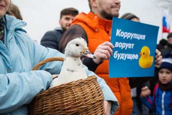 protesters carrying a poster and a duck at an anti-corruption rally in St. Petersburg