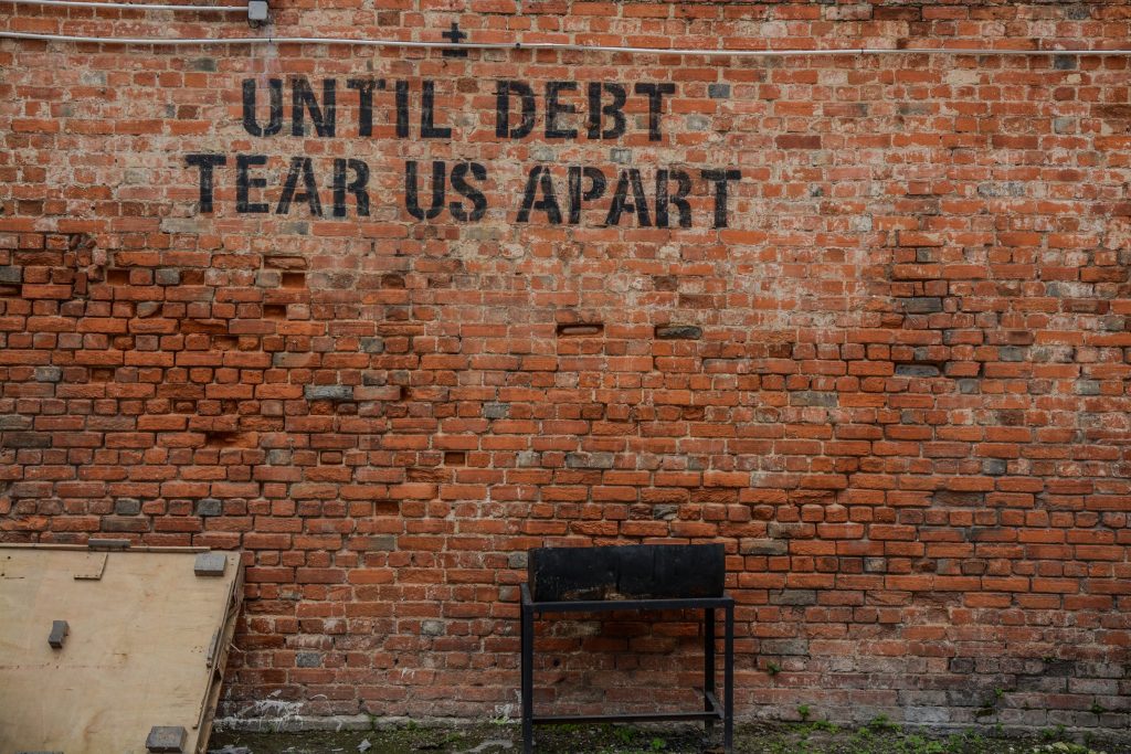 brick wall with the words "until debt tear us apart"