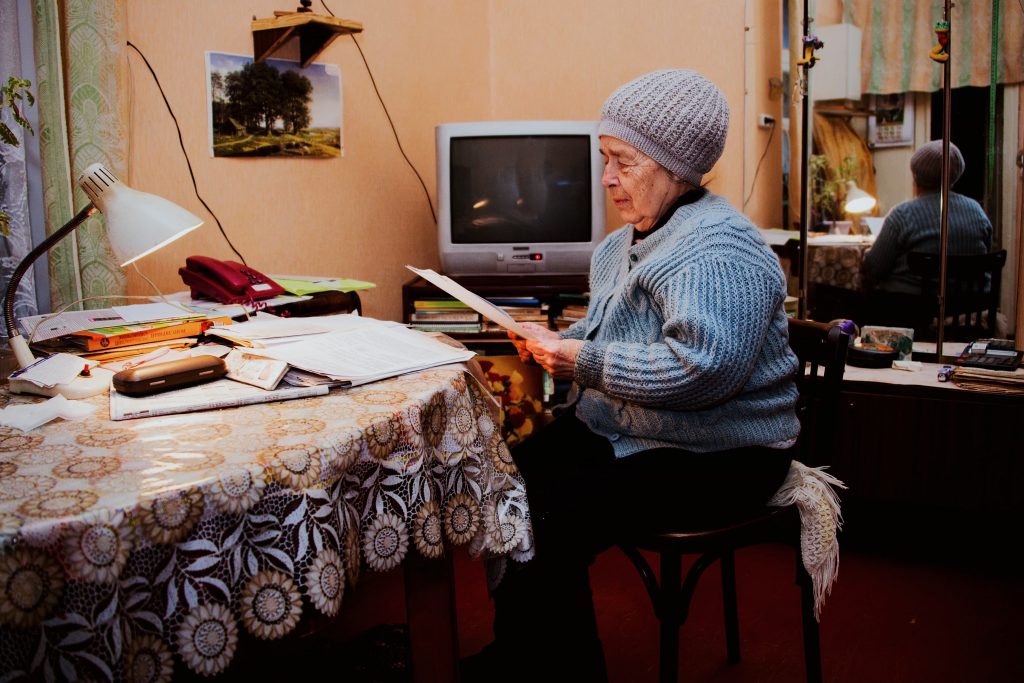 old woman reading in front of the TV